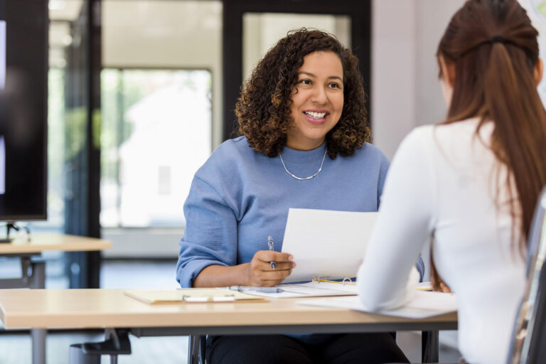 Professional woman in blue sweater during a meeting, representing engaged talent ready to maximize opportunities